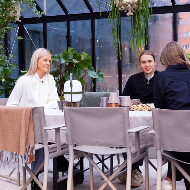 People sitting around a table in a greenhouse.